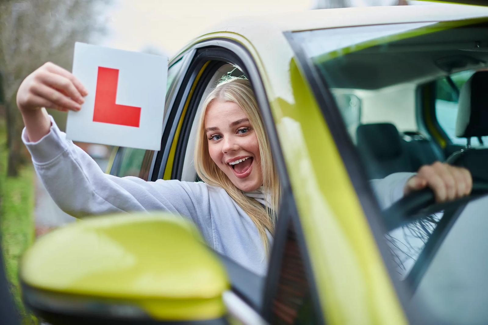 Happy learner driver holding L plate